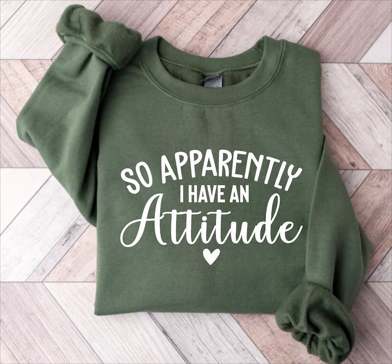 May include: A green sweatshirt with the text "So Apparently I Have An Attitude" in white lettering with a small white heart below the text.