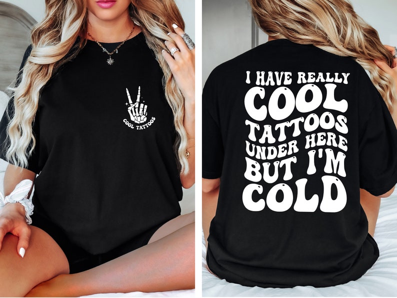 May include: Black t-shirt with a white graphic on the front that says "Cool Tattoos" and a skeleton hand making a peace sign. The back of the shirt has white text that says "I have really cool tattoos under here but I'm cold."