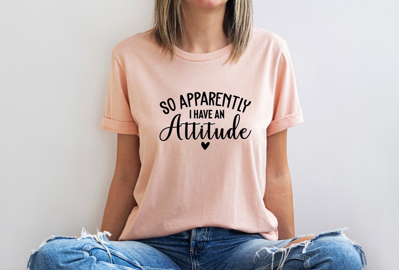 May include: A pink t-shirt with the text "So Apparently I Have An Attitude" in black lettering. A small black heart is below the text.