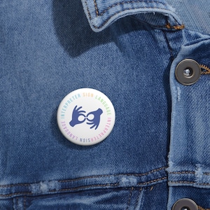 May include: A white button with a blue sign language interpreter symbol and the text "Sign Language Interpreter" in a rainbow color scheme.