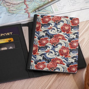 May include: A black leather passport holder with a card slot and a separate pocket for a passport. The holder is open to reveal a credit card and a gold card with the word "GOLD" printed on it. The holder is next to a travel journal with a colorful floral and wave pattern.