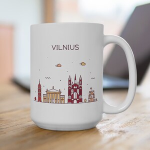 May include: White ceramic mug with a black outline of the Vilnius skyline, including a church, and the word "VILNIUS" in black text.