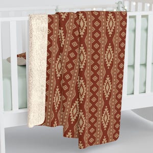 May include: A red and beige throw blanket with a geometric pattern. The blanket is made of soft, plush fabric and is perfect for adding a touch of warmth and style to any room.