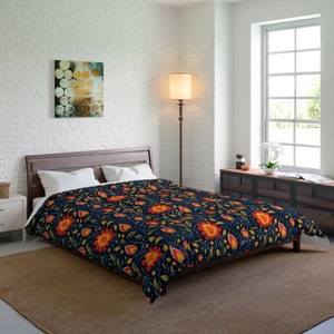 Puede incluir: Una funda nórdica azul marino con un patrón floral con flores amarillas, naranjas y rojas. La funda nórdica está en una cama con almohadas blancas y una cabecera de madera marrón.