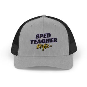 May include: A grey trucker cap with a black mesh back. The front of the cap has the embroidered text "SPED TEACHER Style" in purple and yellow. A star is embroidered next to the word "Style".