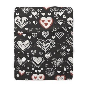 May include: Black and white throw blanket with a repeating pattern of hearts. The hearts are outlined in white and filled with a variety of patterns. Some hearts are filled with a solid red color.