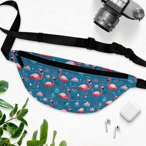 May include: A blue fanny pack with a pink flamingo pattern. The pack has a black adjustable strap.