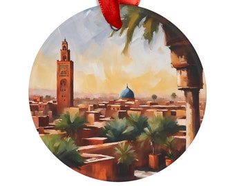 Op de afbeelding: Een ronde, kleurrijk geschilderde ornament met een moskee met een hoge minaret en een blauwe koepel in een stadsbeeld met palmbomen. De ornament heeft een rood lint.