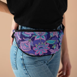 May include: A purple and pink floral patterned fanny pack with a black zipper and black trim.