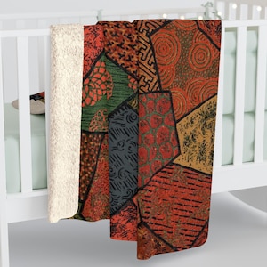 Puede incluir: Una manta de forro polar de patchwork con un patrón geométrico en tonos rojos, verdes, negros y marrones. La manta está hecha de forro polar suave y mullido, perfecta para acurrucarse en el sofá.