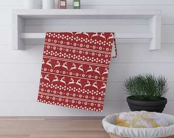 May include: Red kitchen towel with a white snowflake and reindeer pattern hanging on a white shelf.