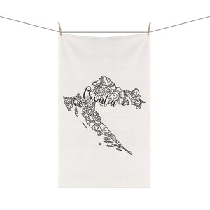 May include: A white kitchen towel featuring a black and white outline of Croatia with the word "Croatia" written in cursive inside the outline.