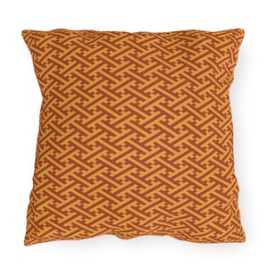 May include: A square throw pillow with a geometric pattern in shades of orange and brown. The pattern is a repeating design of interlocking squares and rectangles.