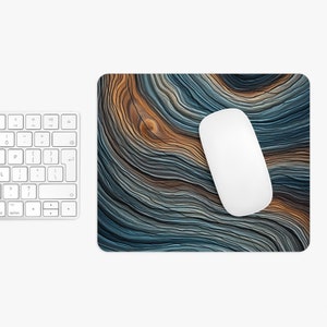 May include: A blue and brown abstract mouse mat with a white computer mouse on top. The mouse mat has a wavy, wood-grain pattern.