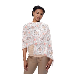 May include: A white scarf with a geometric pattern in shades of pink, brown, and gray. The scarf has a fringed edge.