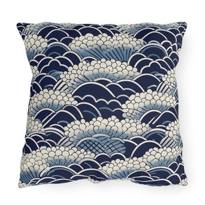 May include: A navy blue throw pillow with a white and blue floral pattern. The pattern features stylized waves and flowers.