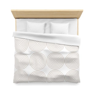 May include: White bedding with a beige concentric circle pattern. The bedding is on a wooden bed frame with two white pillows.