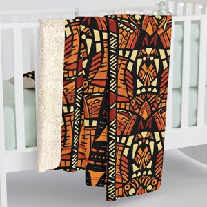 May include: A soft, plush throw blanket featuring a geometric pattern in shades of orange, yellow, and black. The design incorporates abstract shapes and lines, reminiscent of tribal art.