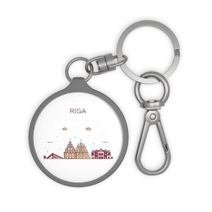 May include: A silver keychain with a round, gray charm featuring a line drawing of the Riga skyline and the word "RIGA" in red.