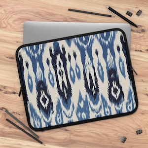 May include: A blue and white ikat patterned laptop sleeve with a black zipper. The sleeve is made of a soft, durable material and is designed to protect your laptop from scratches and bumps.