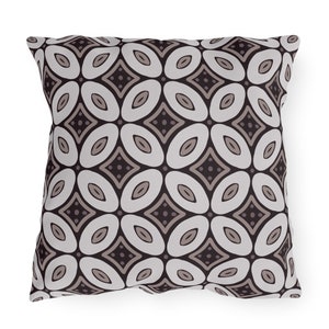 Op de afbeelding: Een decoratief kussen met een geometrisch patroon in tinten bruin en wit. Het patroon bestaat uit herhalende ovalen en ruiten.