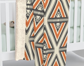 May include: A soft, plush throw blanket with a geometric pattern in shades of orange, black, and cream. The blanket has a sherpa backing and is perfect for adding a touch of warmth and style to any room.