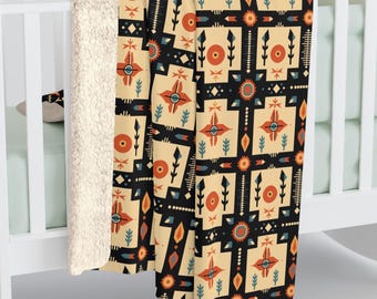 May include: A soft, plush throw blanket with a geometric pattern in shades of orange, yellow, blue, and black. The pattern features stylised arrows, circles, and squares.