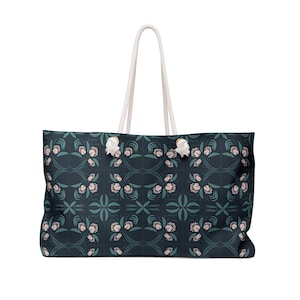 May include: A dark blue tote bag with a white rope handle and a floral pattern. The pattern features pink and teal flowers on a dark blue background.
