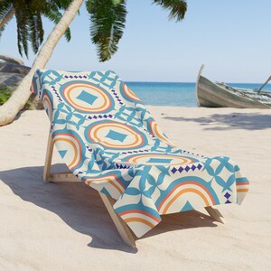 May include: A beach chair with a colorful patterned beach towel. The towel has a geometric design with blue, orange, and white circles and diamonds.