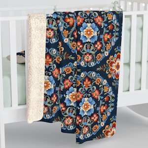 May include: A navy blue fleece throw blanket with a floral pattern. The pattern features red, orange, blue, and green flowers in a circular design.