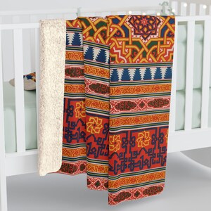 May include: A red, orange, yellow, blue and green patterned fleece throw blanket with a white sherpa backing. The blanket features a geometric design with intricate details.