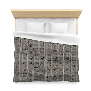 May include: Black and white geometric patterned duvet cover with a white headboard and two white pillows.