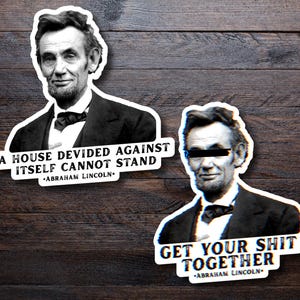 May include: Two stickers with a black and white image of Abraham Lincoln. One sticker reads "A HOUSE DIVIDED AGAINST ITSELF CANNOT STAND" and the other says "GET YOUR SHIT TOGETHER". Both stickers have the text "ABRAHAM LINCOLN."
