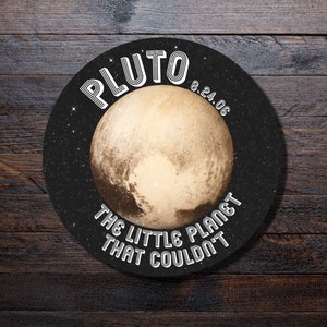 May include: Round Pluto-themed coaster with a detailed image of the planet. The coaster features the word "PLUTO" in a retro font, the date "8.24.06", and the phrase "THE LITTLE PLANET THAT COULDN'T" in white text against a black background with stars.