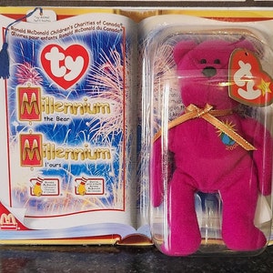 Puede incluir: Un peluche magenta de Millennium the Bear, aún en su embalaje original. El embalaje tiene forma de libro y contiene el texto "Millennium the Bear" y "Ronald McDonald Children's Charities of Canada."