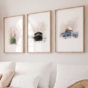 May include: Three framed watercolor paintings of Islamic architecture. The paintings are in a living room setting with a white couch, a woven rug, and a wicker coffee table.
