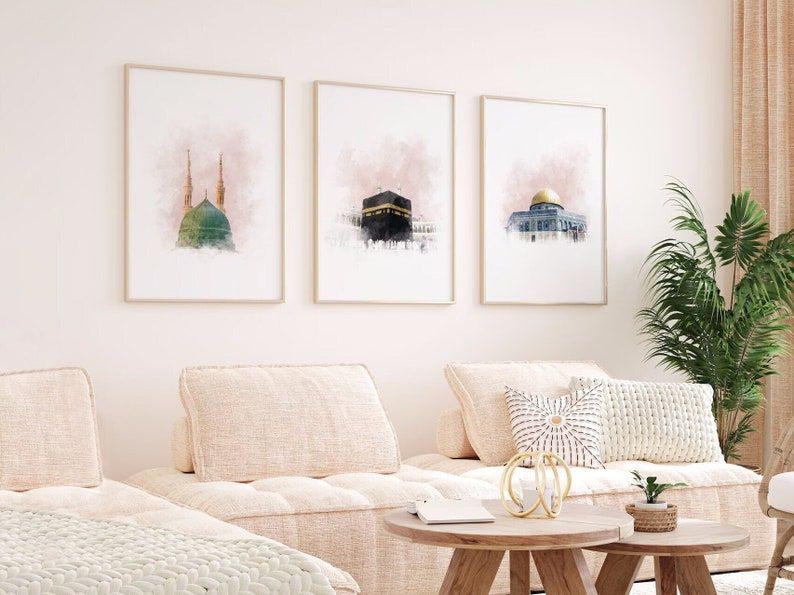 May include: Three watercolor prints of Islamic architecture. The prints are framed in gold and have a pink watercolor background. The prints are hung on a white wall.