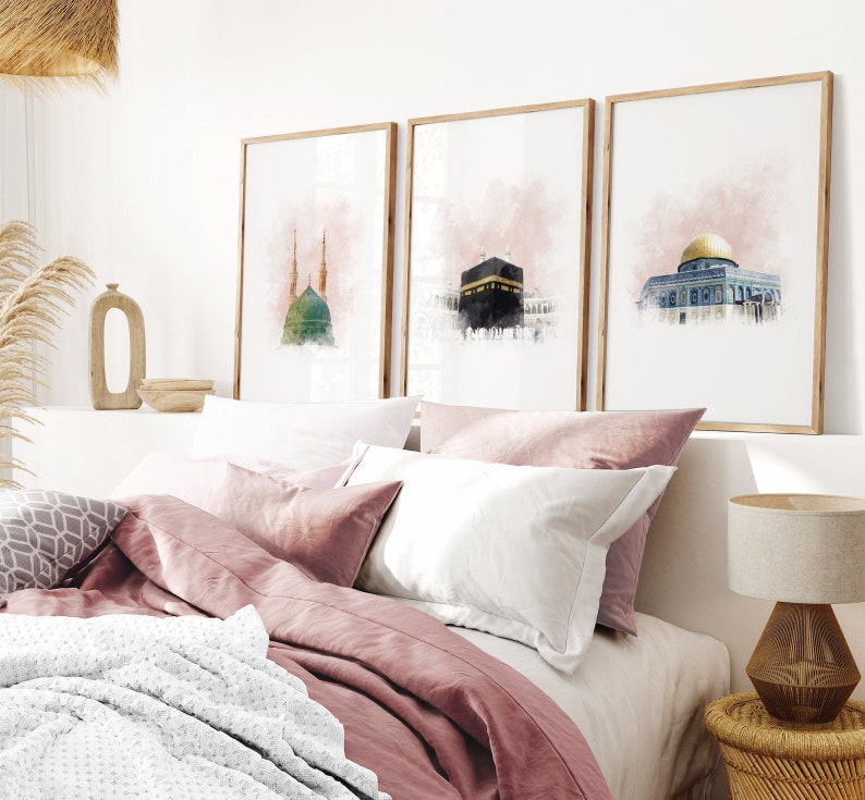 May include: Three framed watercolor paintings of Islamic architecture. The paintings are in a bedroom setting above a bed with pink bedding and a white blanket.