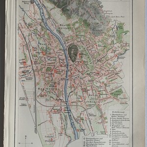 Könnte beinhalten: Eine Vintage-Karte von Graz, Österreich, im Maßstab 1:36.000. Die Karte zeigt die Straßen, Parks und Sehenswürdigkeiten der Stadt, darunter die Mur, den Schlossberg und den Zentralfriedhof. Die Karte ist in Schwarz, Rot und Grün auf weißem Hintergrund gedruckt.