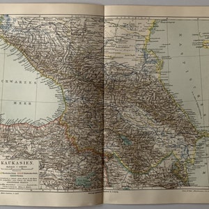 May include: A vintage map of the Caucasus region, showing the Black Sea, the Caspian Sea, and the surrounding mountains. The map is printed in black, brown, and yellow, with a scale of 1:4000000. The map is titled "Kaukasien" and includes a key with symbols for mountains, rivers, and cities.