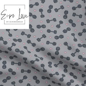 May include: A gray fabric with a repeating pattern of gray dumbbells and small pink hearts. The text "Euro Love" is in a black box in the upper left corner. The text "BY SCRIBESWEAR" is below the Euro Love text.