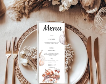 May include: A menu card with the word "Menu" at the top, featuring watercolor illustrations of pumpkins and a Thanksgiving dinner. The menu lists entree, main course, and dessert options. The card is set on a white plate with gold silverware and floral decorations.