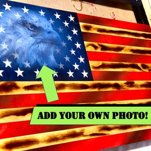 May include: Wooden American flag with a distressed finish. The flag features red and white stripes, a blue field with white stars, and an eagle graphic. The text "ADD YOUR OWN PHOTO!" is displayed.