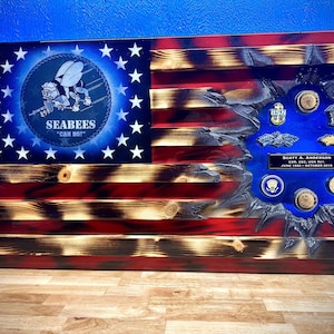 May include: Wooden American flag with a distressed design, featuring the Seabees logo and the text "CAN DO!". Includes a section with military insignia and a nameplate. The flag is red, white, and blue.
