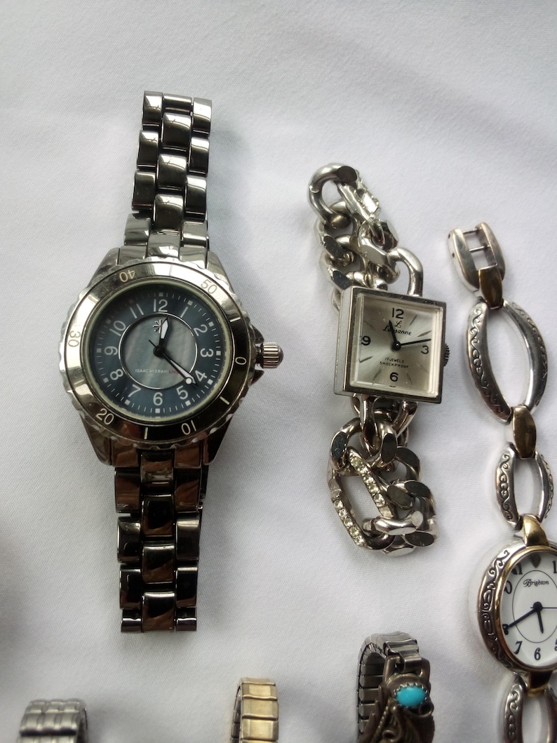 May include: A collection of eight wristwatches with silver, gold, and turquoise accents. The watches have different styles of bands, including chain link, oval link, and a traditional metal band.