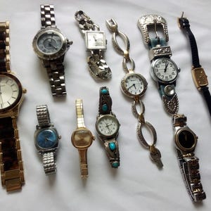 May include: A collection of ten wristwatches with various styles and designs. The watches feature different colored bands, including brown, black, silver, and gold. Some watches have round faces, while others have square or rectangular faces.