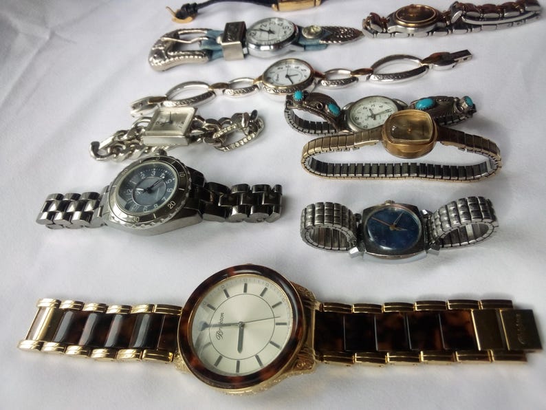 May include: A collection of ten wristwatches with various styles of bands and faces. The watches have silver, gold, and brown bands. Some of the watches have round faces, while others have square faces.