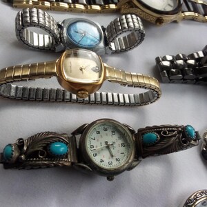 May include: A collection of wristwatches with different styles and designs. Some watches have metal bands, while others have leather bands. The watches have round faces with various colored dials.