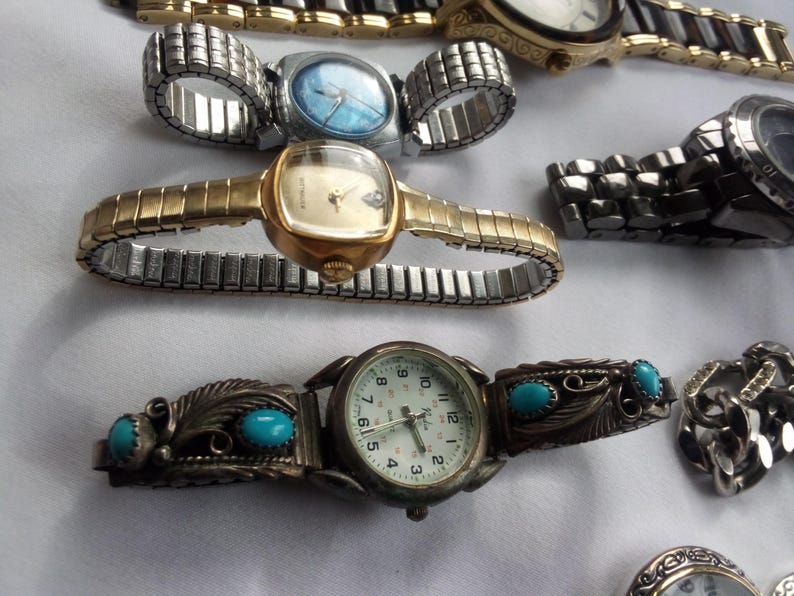 May include: A collection of wristwatches with different styles and designs. Some watches have metal bands, while others have leather bands. The watches have round faces with various colored dials.