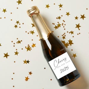 May include: A champagne bottle with a white label that says "Cheers to the New Year 2025". The bottle is surrounded by gold stars.